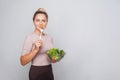 Portrait of attractive fit woman with hair bun holding bawl of fresh vegetable salad and looking at camera