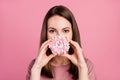 Portrait of attractive funny cunning girl eating fresh doughnut closing mouth isolated over pink pastel color background