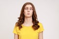 Portrait of attractive funny silly young woman in yellow T- shirt with cross eyed, has stupid dumb