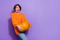 Portrait of attractive funny stunned overwhelmed girl carrying big pumpkin copy space isolated over bright purple violet