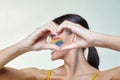 Portrait of an attractive girl with bright makeup, whose hands took the shape of a heart. A rainbow LGBT flag is depicted on her