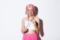 Portrait of attractive girl with pink wig and bright makeup, dressed up as a fairy for halloween party, holding magic Royalty Free Stock Photo