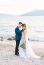 Portrait of an attractive groom and bride standing on nature near the Garda Lake. Happy and joyful moment. Romantic couple of newl