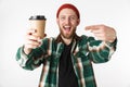 Portrait of attractive guy wearing hat and plaid shirt holding paper cup with coffee, while standing isolated over white Royalty Free Stock Photo