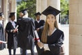 Portrait of attractive, happy graduate student in mortar board cap and ceremonial robes, holding diploma in her hands. Royalty Free Stock Photo