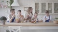 Portrait attractive happy woman and her four teen sons eating pies and drinking orange juice in the kitcken standing at