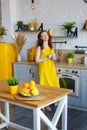 Portrait of an attractive healthy red-haired girl in a yellow sundress with fruit in her hands in the kitchen Royalty Free Stock Photo