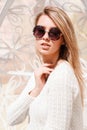 Portrait of an attractive hipster young woman in a fashionable vintage sweater in round stylish sunglasses on a white background.