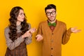 Portrait of attractive irritated couple nervous girl saying pretense to puzzled guy isolated over bright yellow color