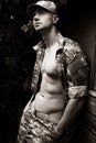 Portrait of attractive male soldier wearing camouflage uniform with open jacket revealing pecs and sixpack abs Royalty Free Stock Photo