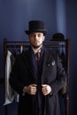 Portrait of attractive man in dark coat and trendy suit indoors tailors