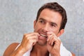 Portrait of attractive man looking in the mirror while flossing hsi teeth Royalty Free Stock Photo