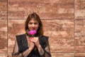 Portrait of attractive mature woman in transparent black shirt, smelling a beautiful flower on a brown marble background. Concept Royalty Free Stock Photo