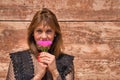 Portrait of attractive mature woman in transparent black shirt, smelling a beautiful flower on a brown marble background. Concept Royalty Free Stock Photo