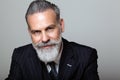 Portrait of attractive middle aged bearded gentleman wearing trendy suit over empty gray background. Studio shot