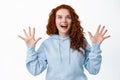 Portrait of attractive natural redhead woman with curly hairstyle, raising hands up to catch something, looking up with