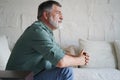 Portrait of attractive pensive senior man sitting in sofa at home and looking at window. Royalty Free Stock Photo