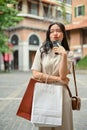 A playful Asian woman posing with a pretty face while carrying her shopping bags on the street Royalty Free Stock Photo