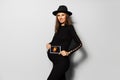 Portrait of attractive pregnant woman, wearing black dress and hat, holding ultrasound scan of her baby. Royalty Free Stock Photo