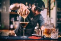 Portrait of attractive professional bartender preparing alcoholic drinks at bar