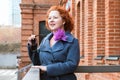 Portrait of an attractive red-haired woman in sunglasses and blue coat with a bright brooch Royalty Free Stock Photo