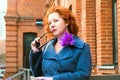 Portrait of an attractive red-haired woman in sunglasses and blue coat with a bright brooch Royalty Free Stock Photo