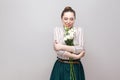 Portrait of attractive romantic pleasure young woman in striped shirt and green skirt holding bouquet of white flowers and hugging Royalty Free Stock Photo