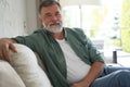 Portrait of attractive senior man sitting in sofa at home. Royalty Free Stock Photo