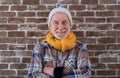 Portrait of attractive senior man wearing winter dress standing against a brick wall looking at camera smiling. Brick wall in Royalty Free Stock Photo