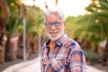 Portrait of attractive senior man white-hair and beard looking at camera. Standing outdoor in a public park at sunset. A smiling Royalty Free Stock Photo