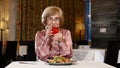 Portrait of attractive senior woman in restaurant tasting fresh fruit drink. Happy senility concept. Smiling and lughing