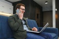 Portrait of an attractive serious young bearded man wearing casual clothes sitting on a couch at the living room Royalty Free Stock Photo