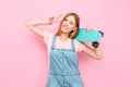 Portrait of an attractive skater girl holding a skateboard and showing a peace sign