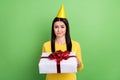 Portrait of attractive skeptic girl holding giftbox dislike unpleasant isolated over green color background