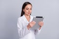 Portrait of attractive skilled focused nurse doctor using tablet reading prescription web over grey pastel