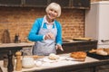 Portrait of attractive smiling happy senior aged woman is cooking on kitchen. Grandmother making tasty baking Royalty Free Stock Photo