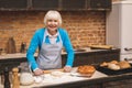 Portrait of attractive smiling happy senior aged woman is cooking on kitchen. Grandmother making tasty baking Royalty Free Stock Photo