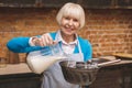 Portrait of attractive smiling happy senior aged woman is cooking on kitchen. Grandmother making tasty baking Royalty Free Stock Photo