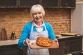 Portrait of attractive smiling happy senior aged woman is cooking on kitchen. Grandmother making tasty baking Royalty Free Stock Photo