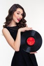 Portrait of attractive smiling retro styled woman holding vinyl record