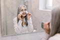 Portrait of attractive smiling senior woman with natural gray hair, cleaning her face with cotton pads, caring for her Royalty Free Stock Photo