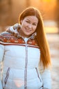 Portrait of attractive smiling woan in white down jacket in sunlight