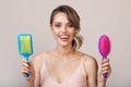 Portrait of attractive smiling woman holding hairbrushes Royalty Free Stock Photo