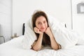 Portrait of attractive smiling woman relaxing in bed, lying covered in white sheets and warm duvet in morning, looking Royalty Free Stock Photo