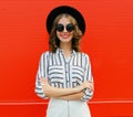 Portrait of attractive smiling woman wearing a black round hat and striped white shirt over a red Royalty Free Stock Photo