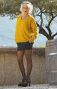 Portrait of attractive and smiling woman with yellow sweater, black miniskirt and fishnet stockings Royalty Free Stock Photo