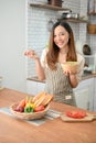 Portrait of an attractive and smiling young Asian woman wearing apron, holding a salad bowl Royalty Free Stock Photo