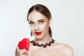 Portrait on attractive, smiling young woman in beautiful necklace, holding in her hand red heart, looking at camera, isolated on Royalty Free Stock Photo