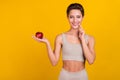 Portrait of attractive sportive cheerful girl holding on palm apple healthy nutrition isolated over bright yellow color Royalty Free Stock Photo