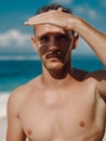 Portrait of attractive tanned man on tropical beach. Sexy caucasian man looking at camera